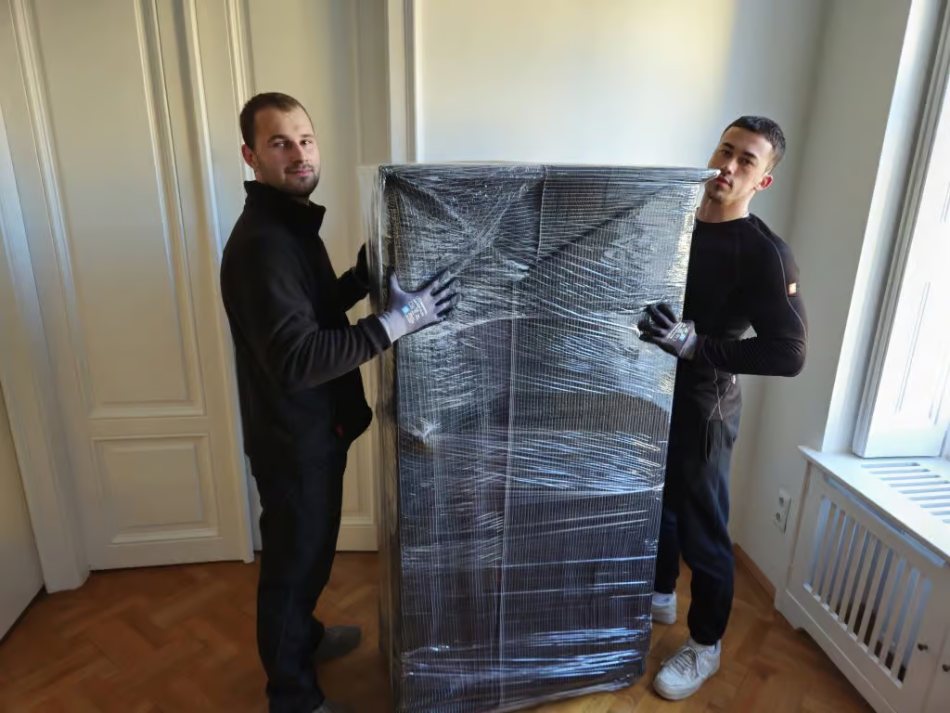 FlexiTrans-Möbelpacker tragen einen verpackten Schrank